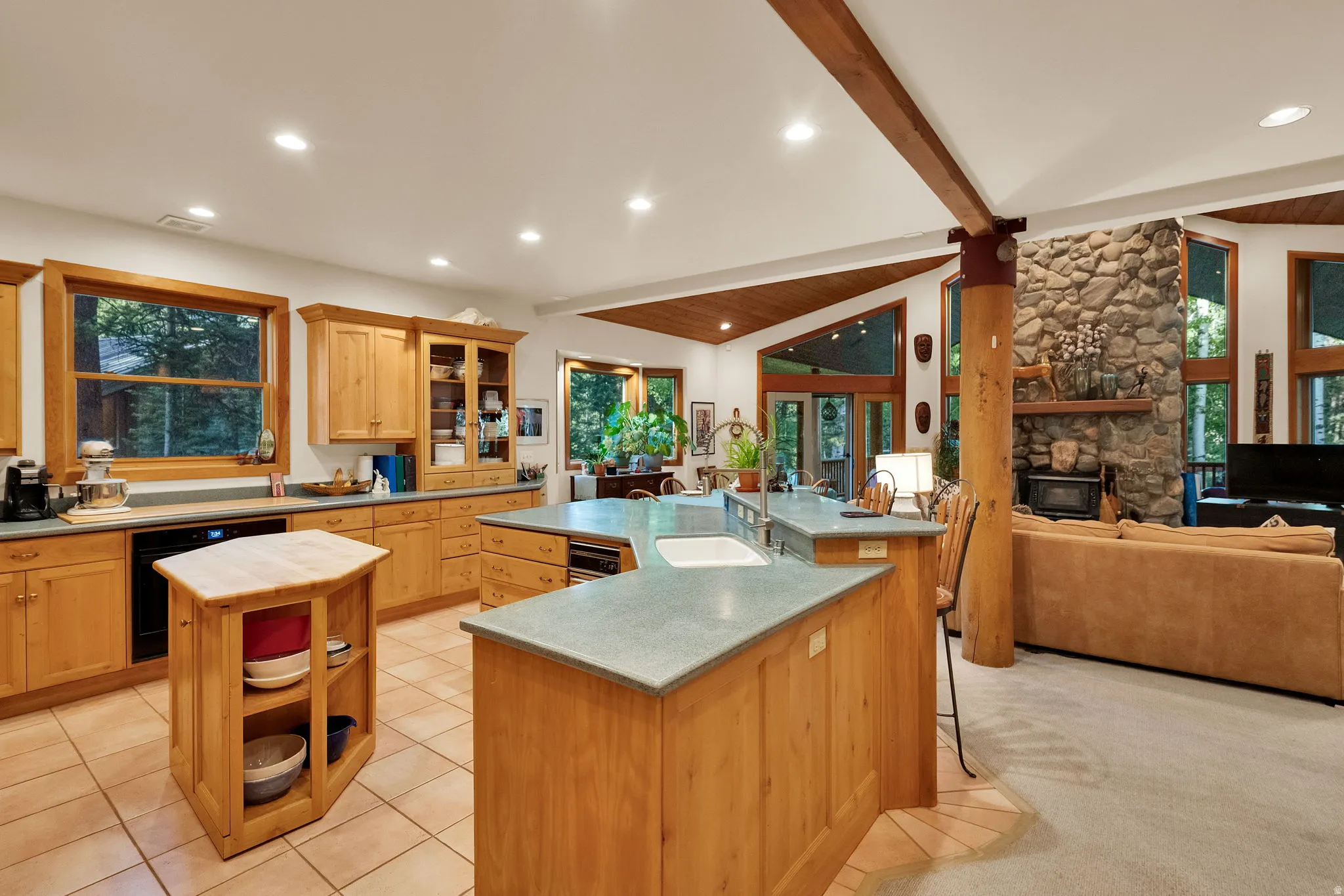 Spacious kitchen featuring light wood cabinetry, stone-look countertops, and tile flooring