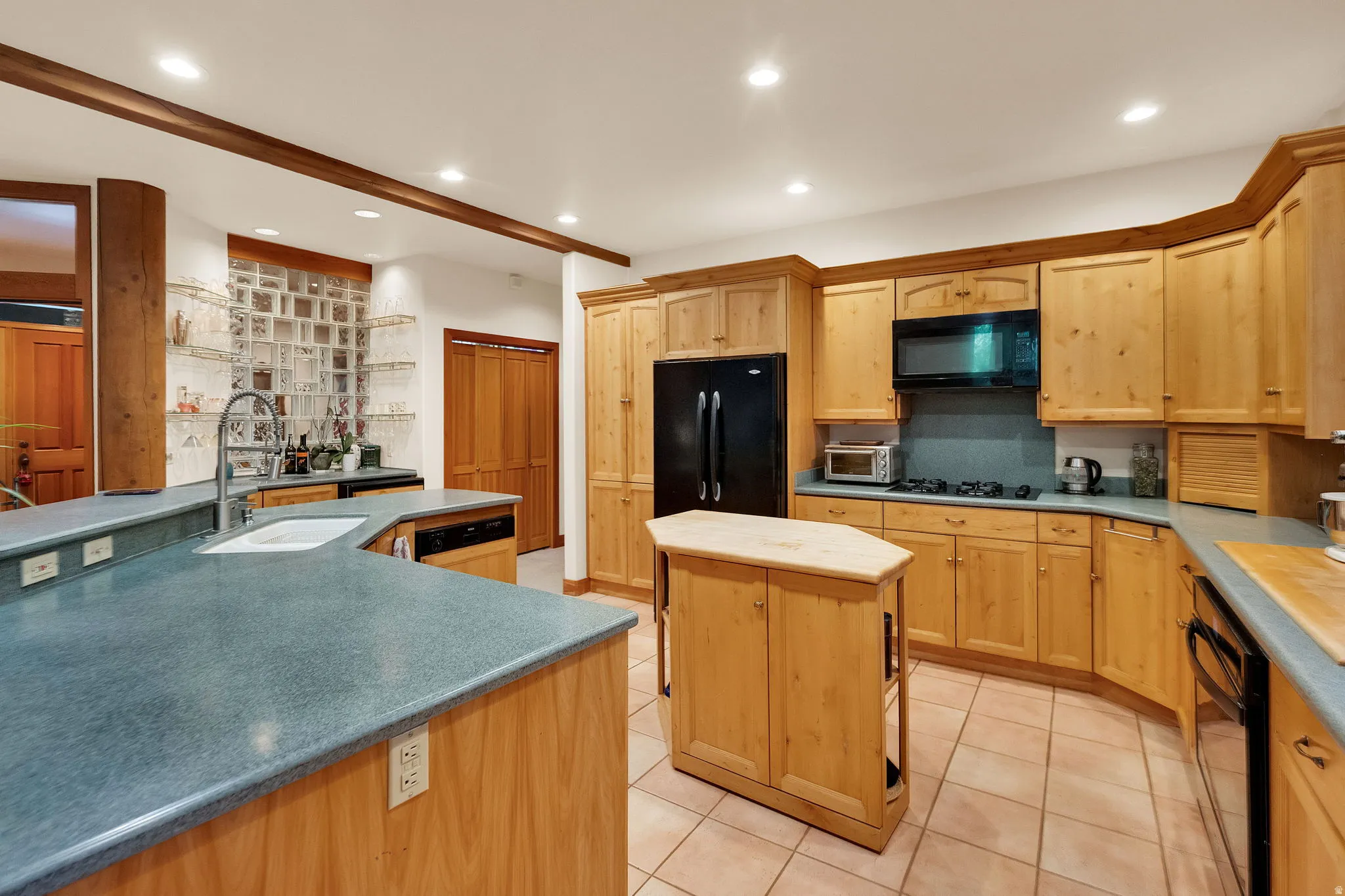 Kitchen featuring light wood cabinetry, a central island, and complementary blue-toned countertops