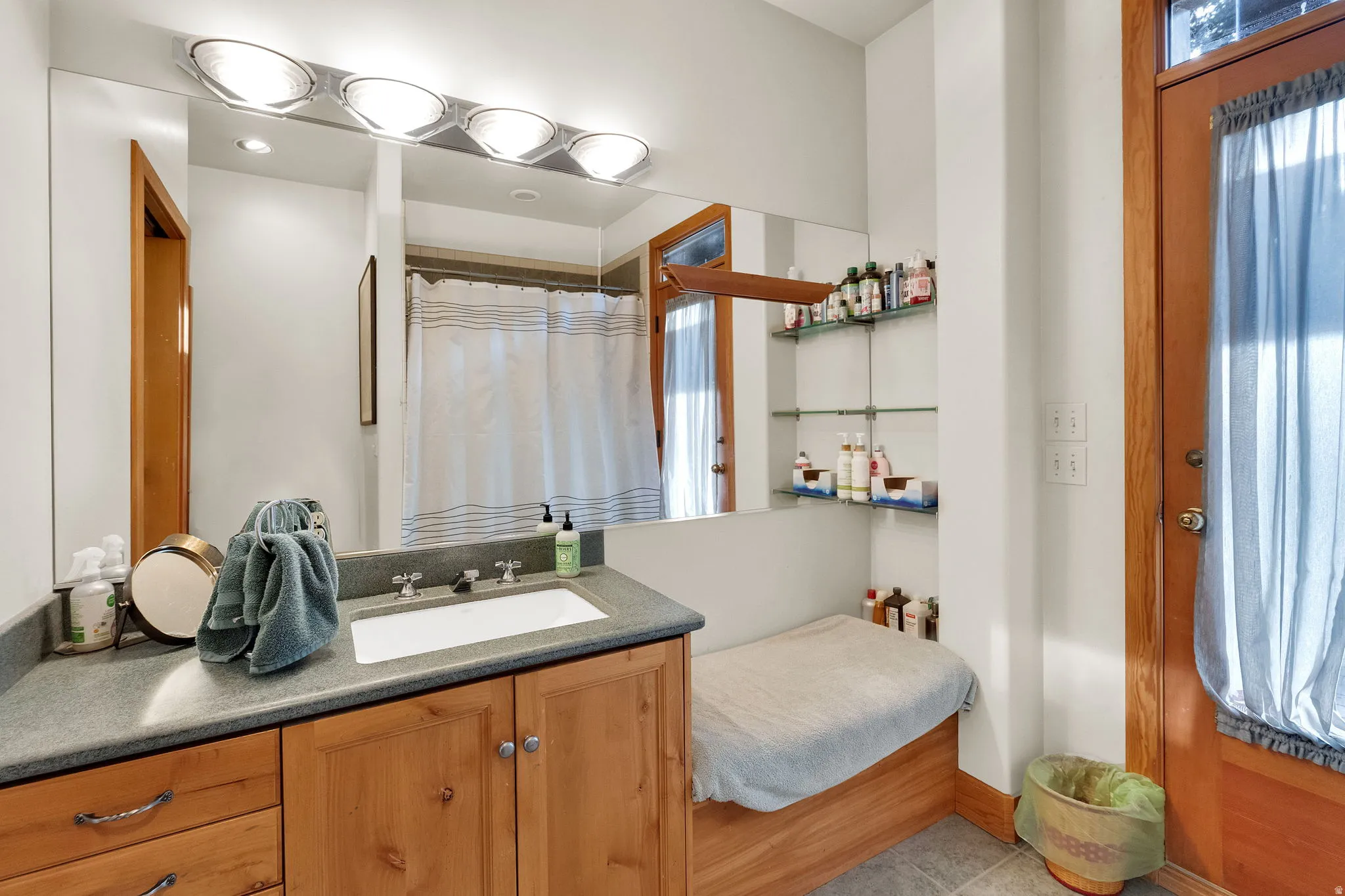 Bathroom featuring a wood vanity with integrated sink, a large wall-mounted mirror, and a four-light vanity fixture