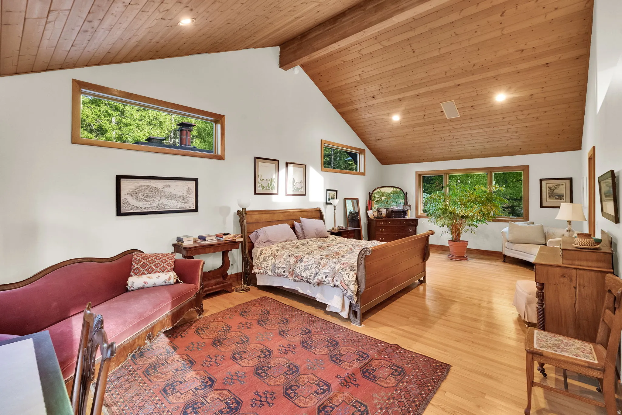 Spacious room featuring vaulted wood-paneled ceilings, warm wood-finish flooring, and white walls