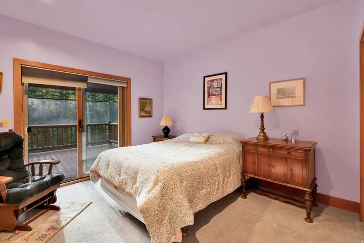 Carpeted room featuring a large sliding glass door with wood trim, opening to an exterior deck