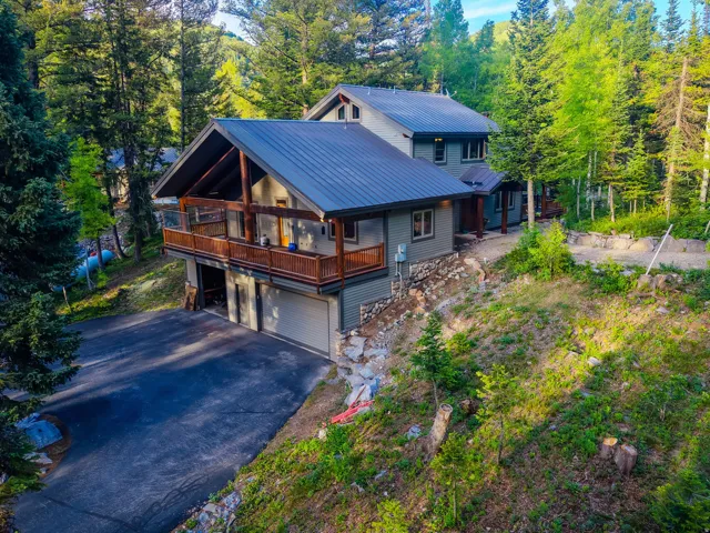 Multi-level residence featuring a dark metal roof, natural wood accents, and a two-car garage