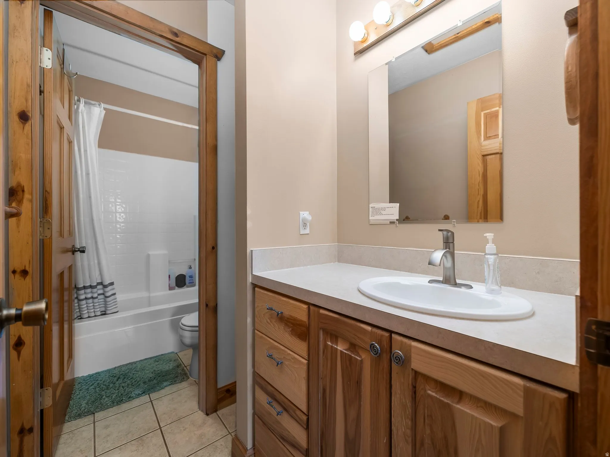 Bathroom featuring vanity, shower / bathtub combination with curtain, and light tile patterned floors