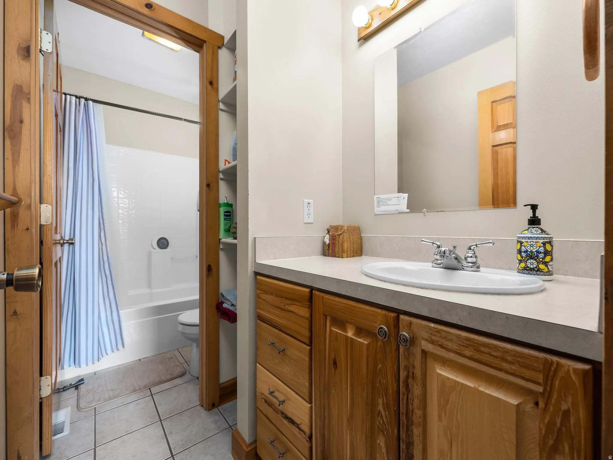 Bathroom with vanity, shower / bath combo with shower curtain, and light tile patterned floors