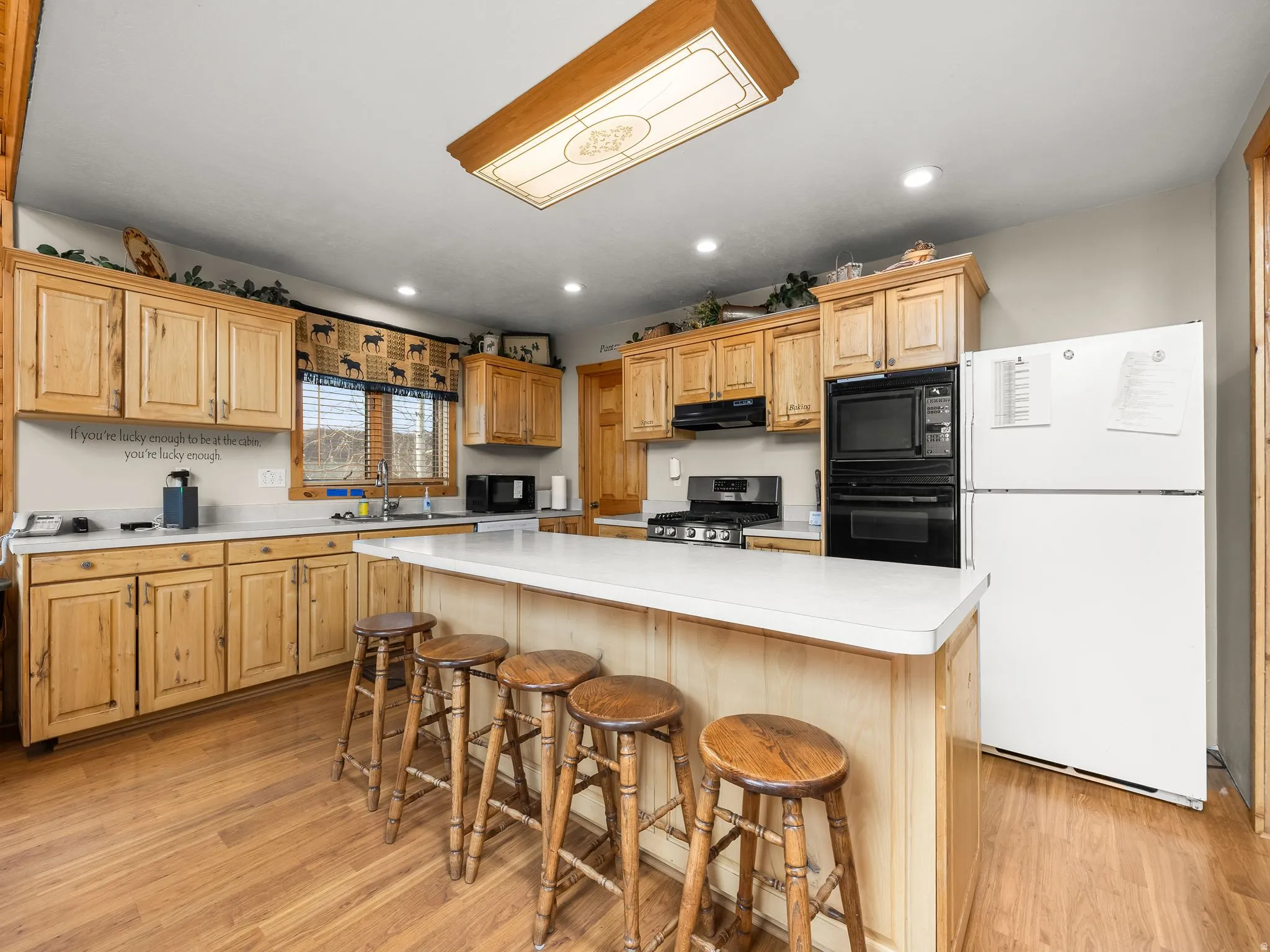 Kitchen with black appliances, light countertops, a kitchen breakfast bar, a center island, and recessed lighting