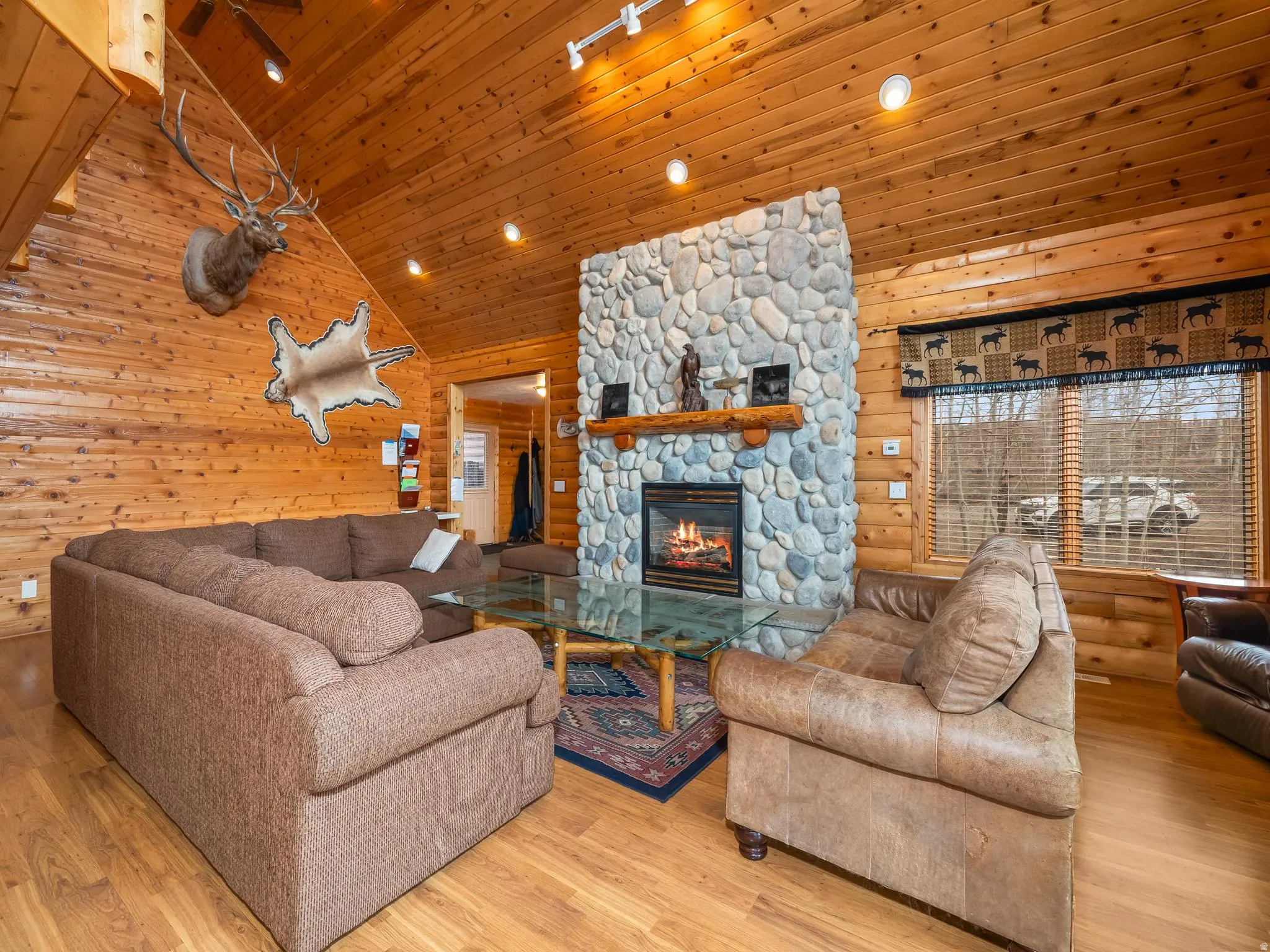 Living area featuring a fireplace, a vaulted wood ceiling, light wood-style floors, wooden walls, and recessed lighting
