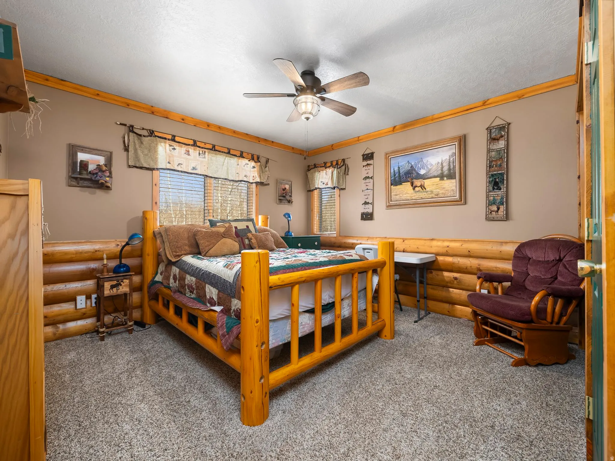 Carpeted bedroom with log walls, ceiling fan, a textured ceiling, and ornamental molding