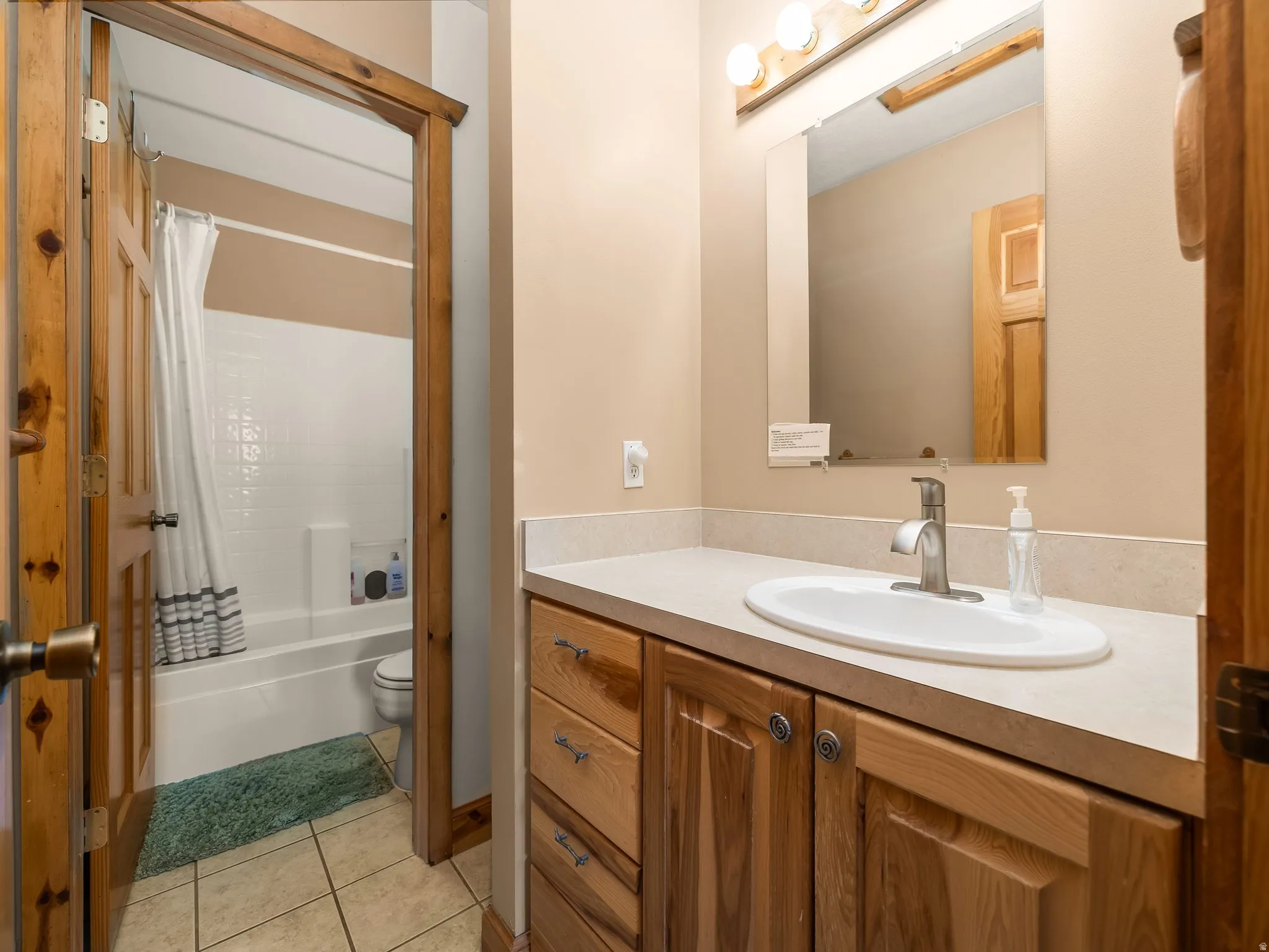 Full bath with vanity, shower / bath combo, and light tile patterned flooring