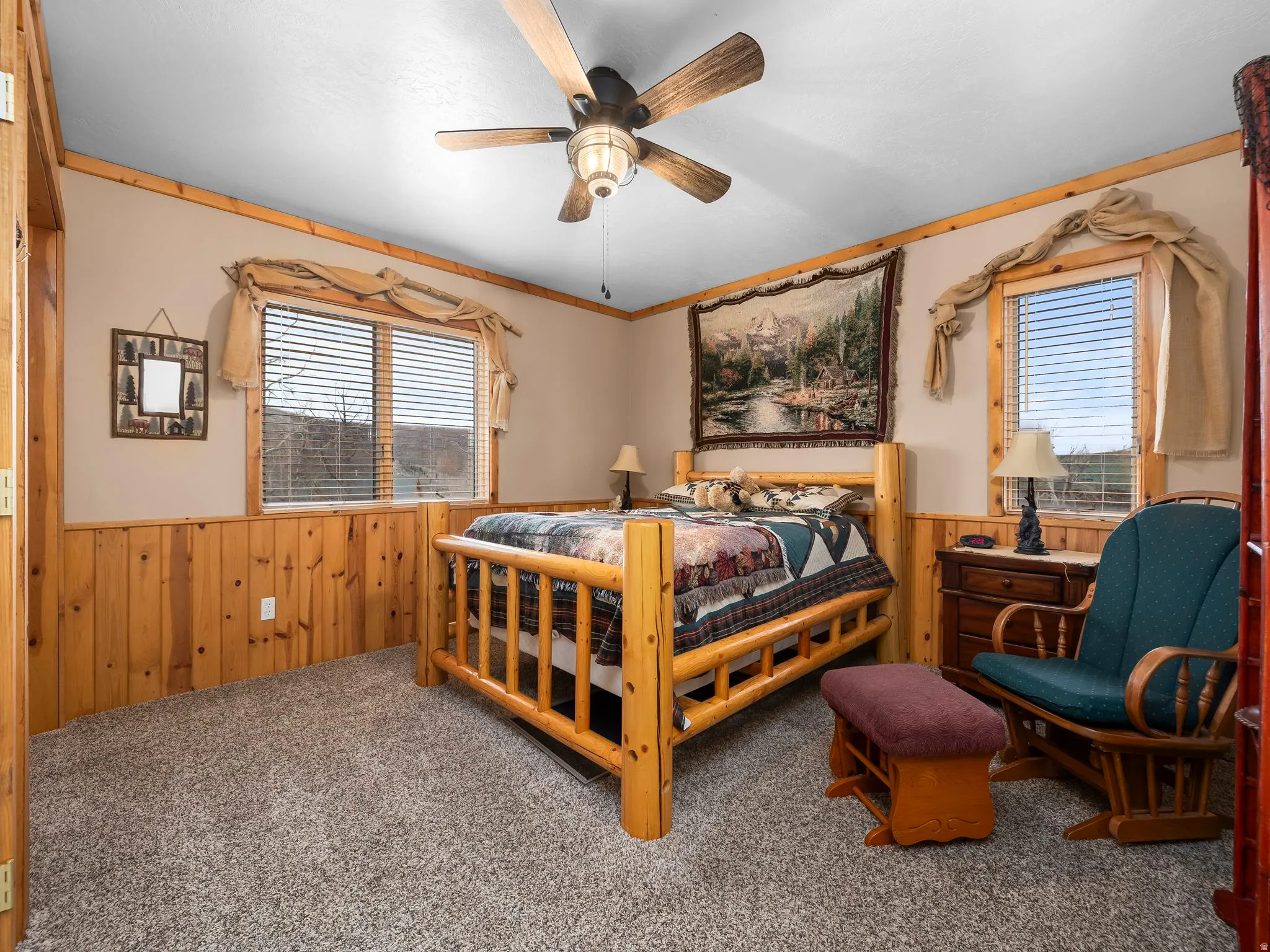 Bedroom featuring wood walls, a wainscoted wall, carpet flooring, and ceiling fan