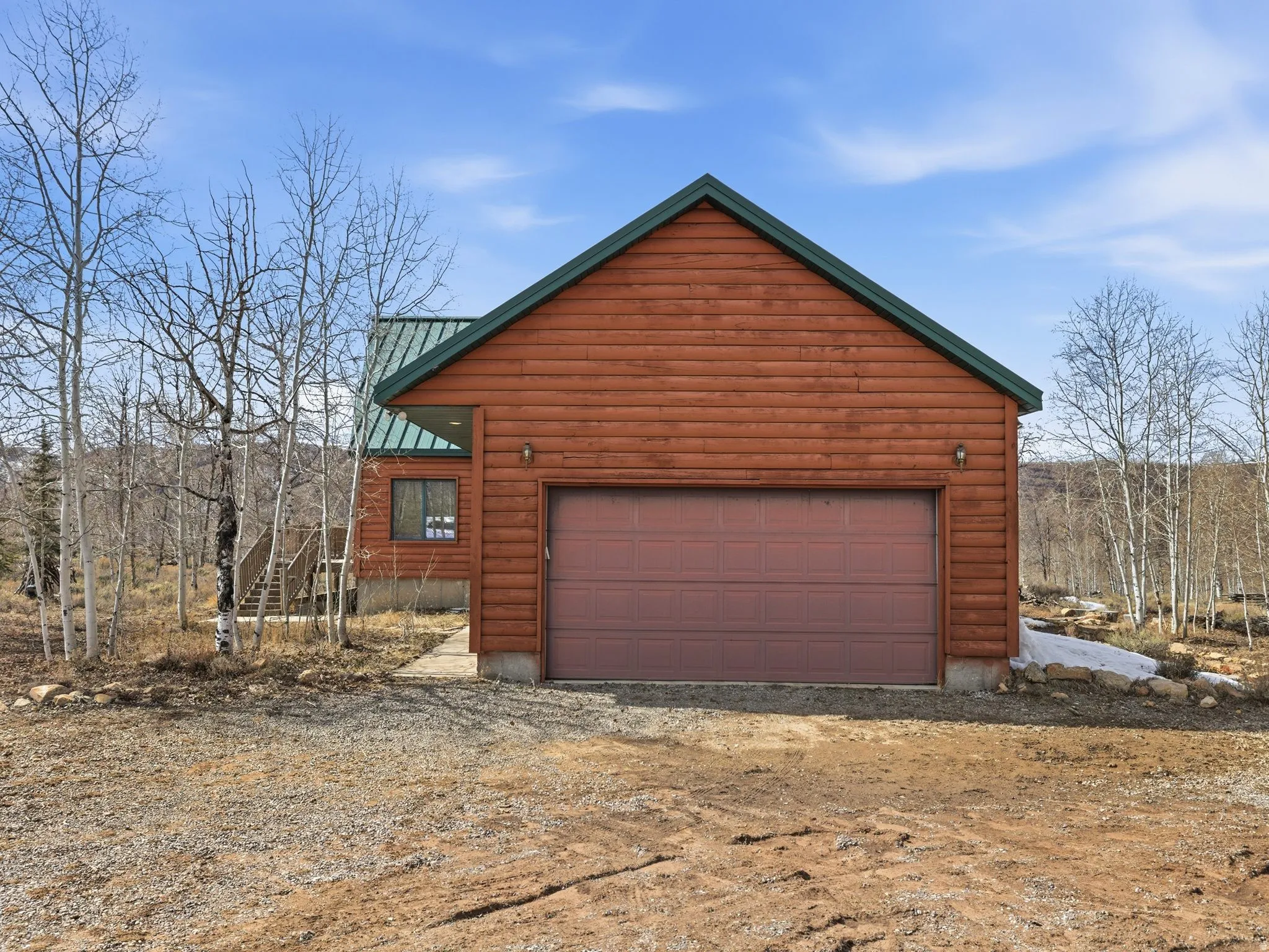 View of property exterior with a metal roof and driveway