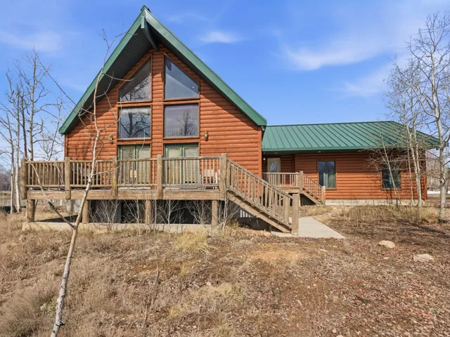 Back of house with faux log siding, a wooden deck, and a standing seam roof