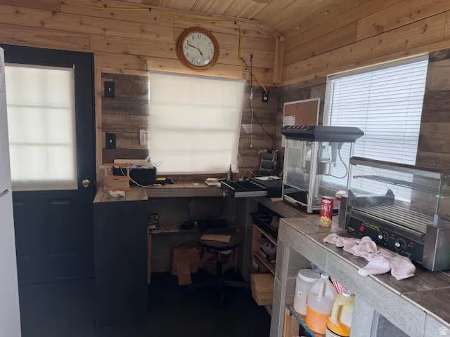 Home office with a vaulted wood ceiling and wood walls