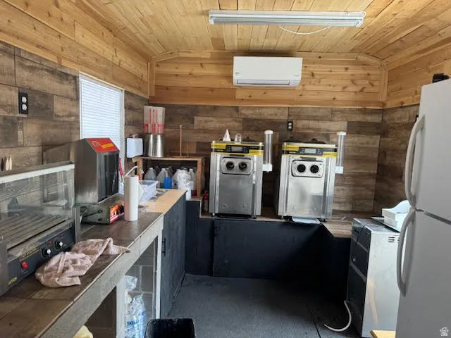 Kitchen with freestanding refrigerator, a vaulted wood ceiling, and wooden walls