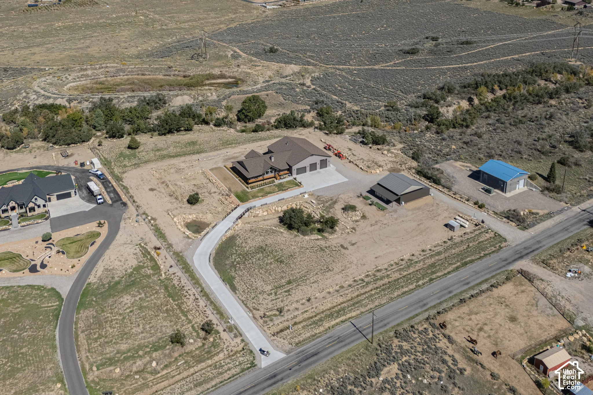 Expansive property featuring a concrete driveway, attached multi-car garage, and detached outbuilding with a metal roof