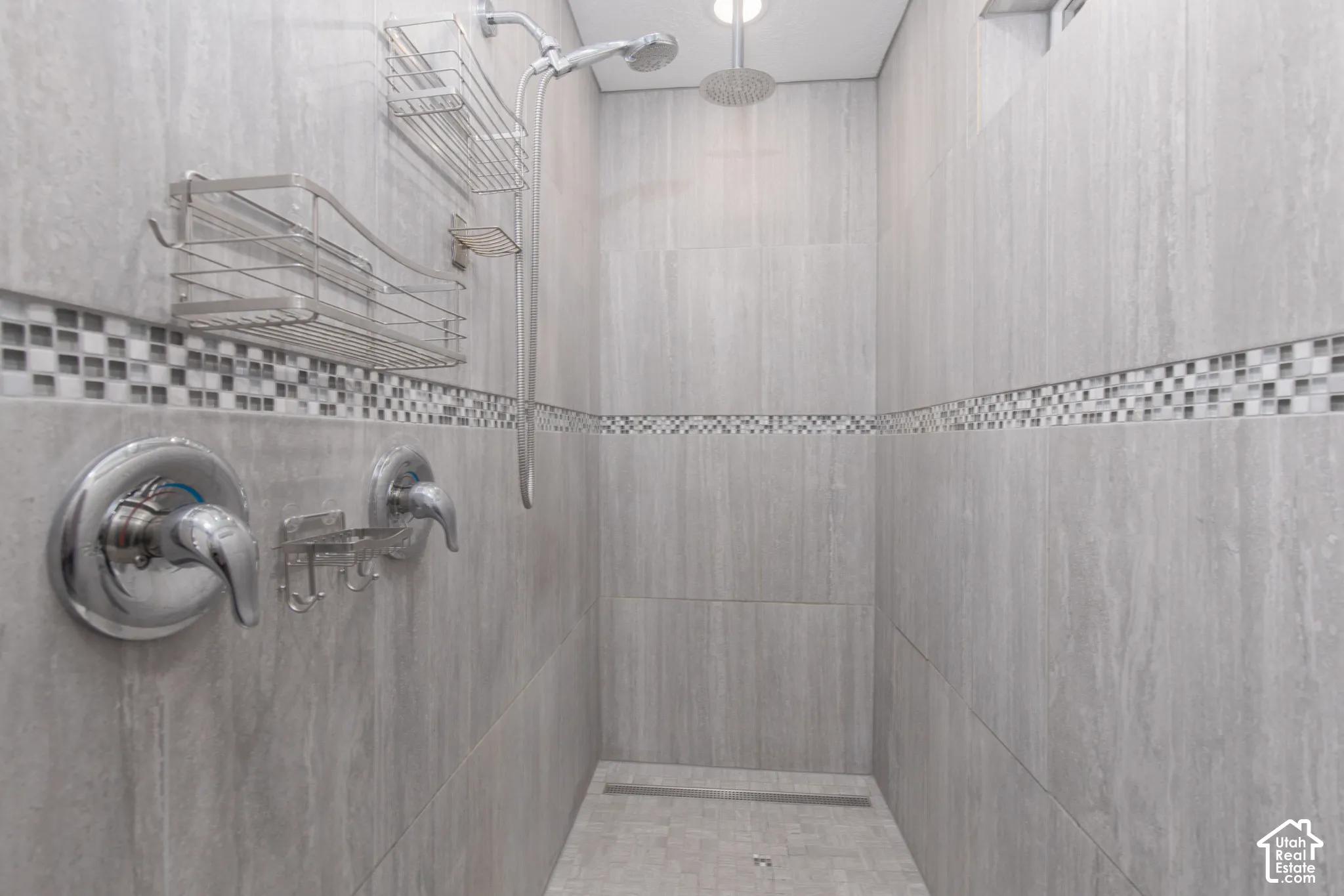 Tiled shower with a linear drain, mosaic tile accent, and a rainfall shower head