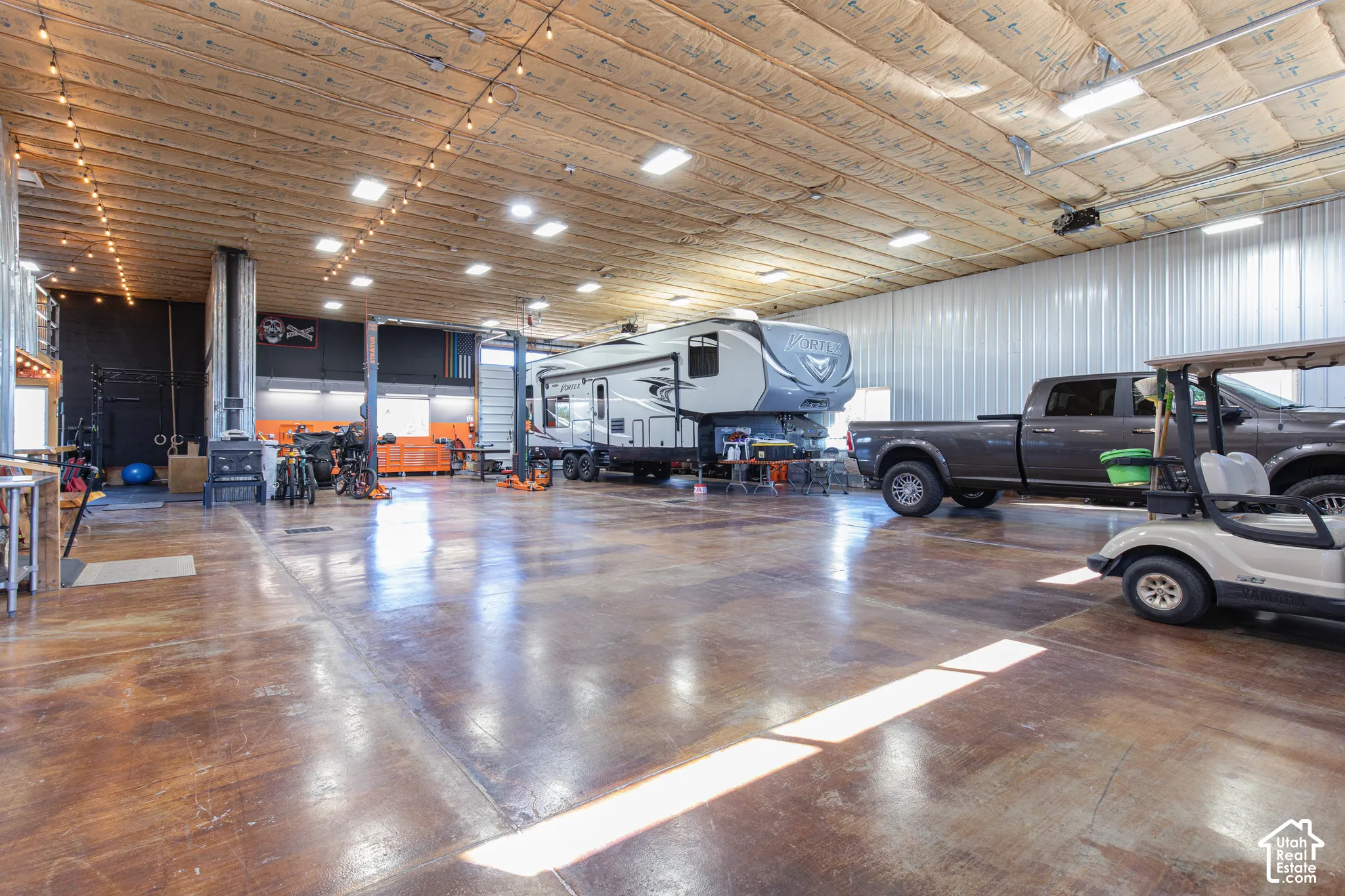 Spacious garage with polished concrete flooring, exposed ceiling with string lighting, and ample overhead lighting