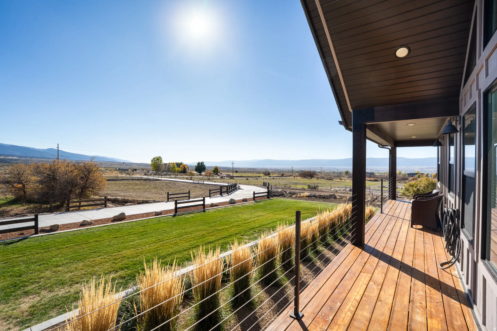 Wooden terrace featuring a rural view, a mountain view, and a lawn