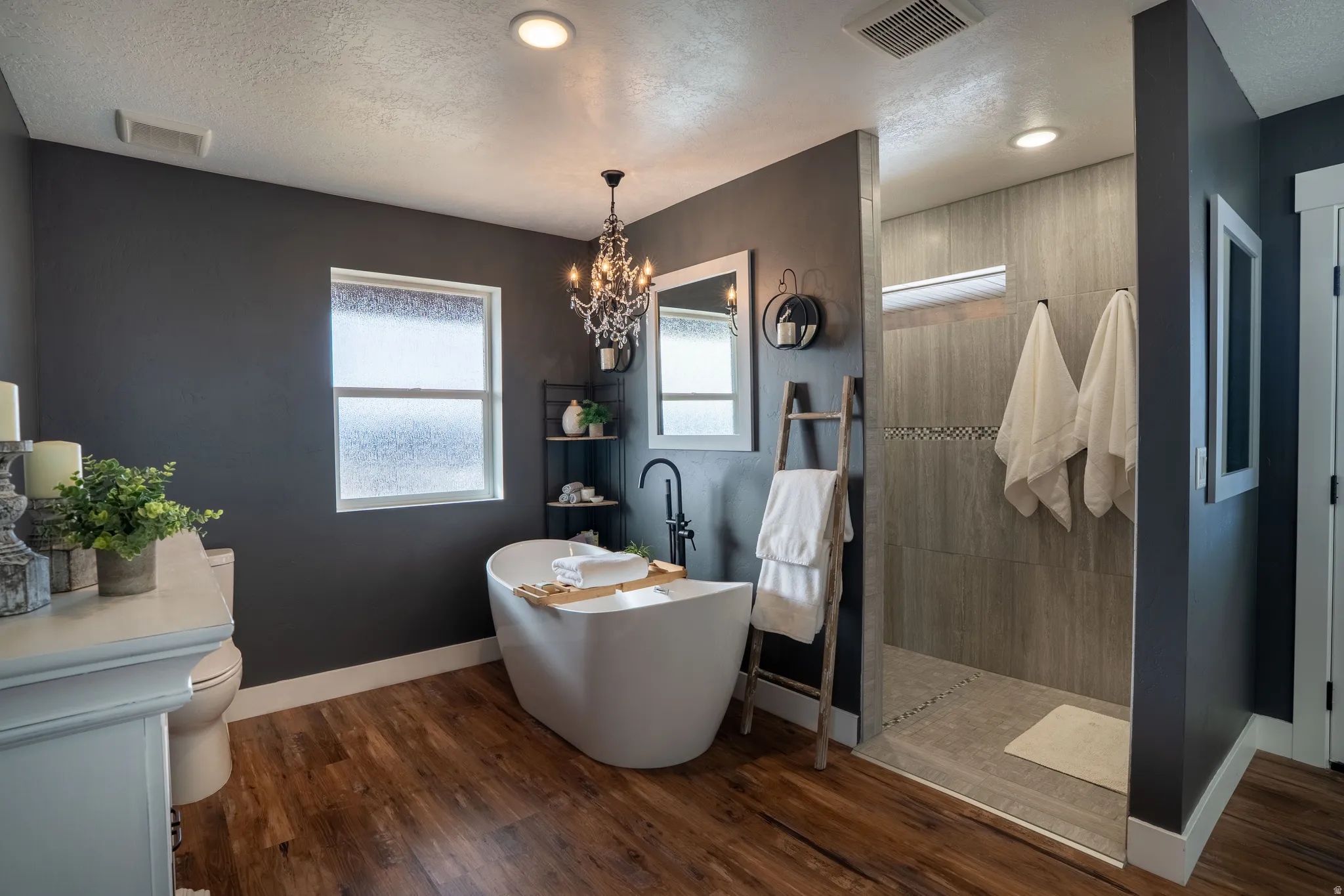 Full bathroom a roll-in shower, a soaking tub, hanging lights, separate tub