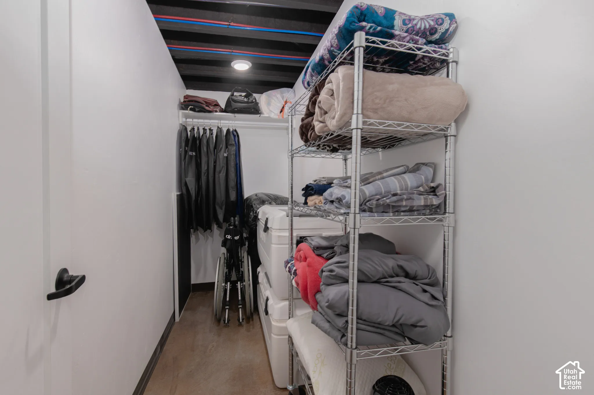 Built-in shelving and hanging rod storage system within a compact space, featuring a recessed ceiling light and wood-finish flooring