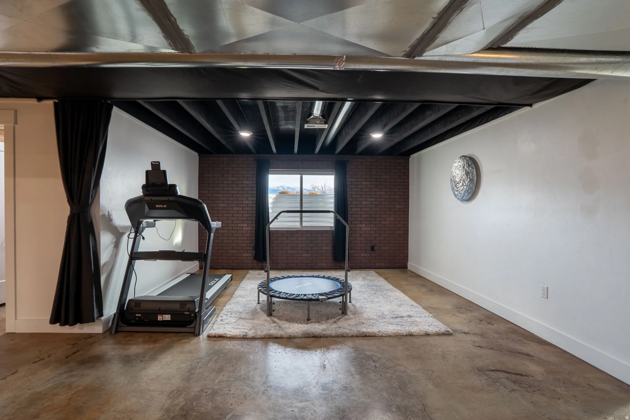 Flex room, potential 5th bedroom with concrete flooring and brick wall, curtain to close off space