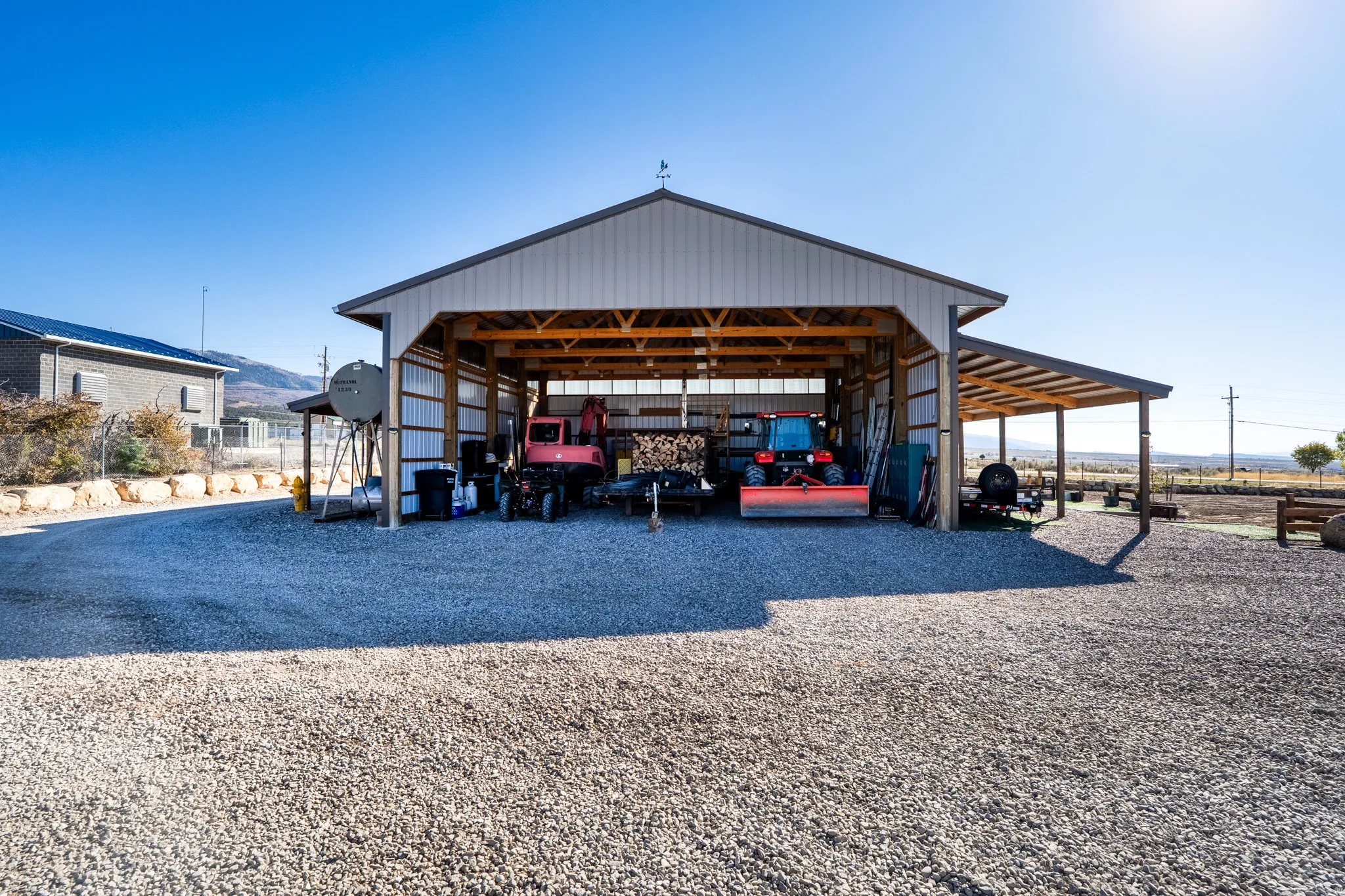 View of pole barn featuring a carport and driveway, overhangs