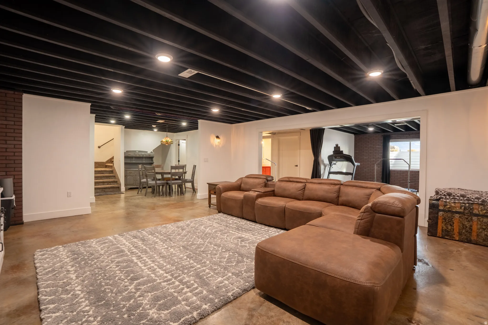Living room featuring concrete flooring, sitting area, and stairs