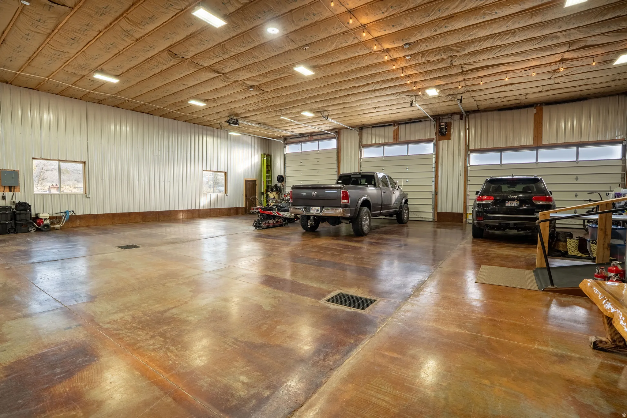 Garage featuring metal wall and electric panel and garage doors