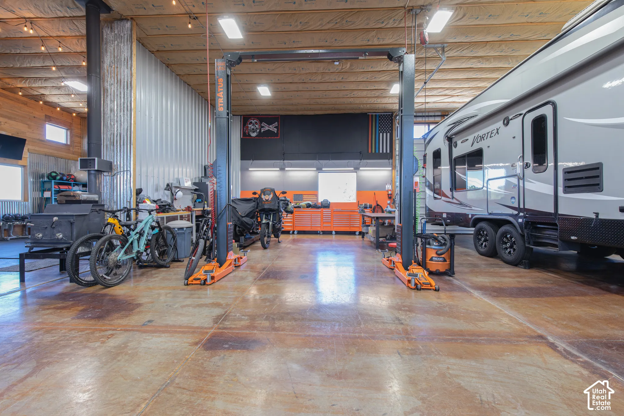 Spacious garage with high ceilings, exposed wood beams, concrete flooring, and metal paneling