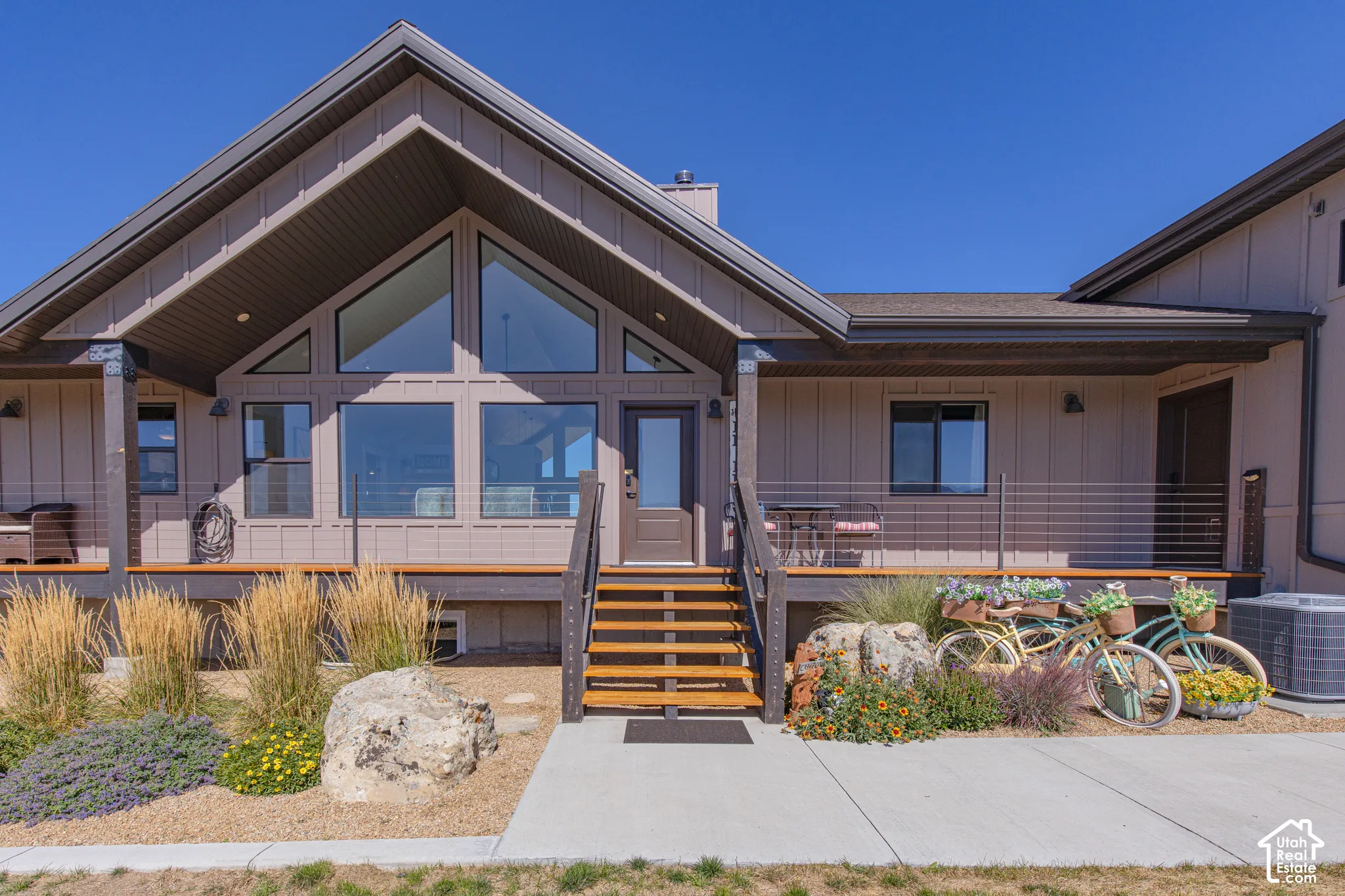 Modern architectural style with a prominent A-frame facade, extensive window placement, and a full-width deck