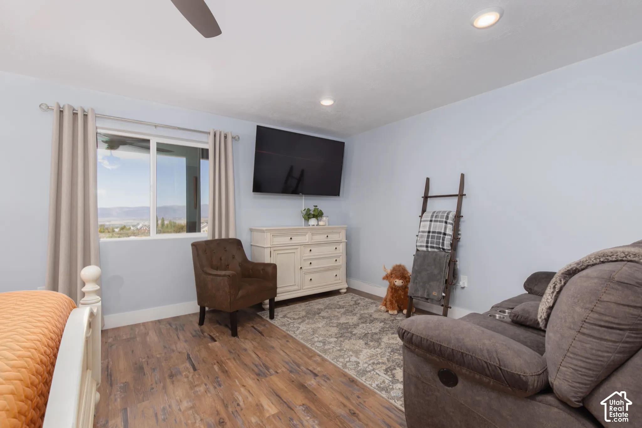 Recessed lighting, wood-finish flooring, ceiling fan, and a large window with distant scenery