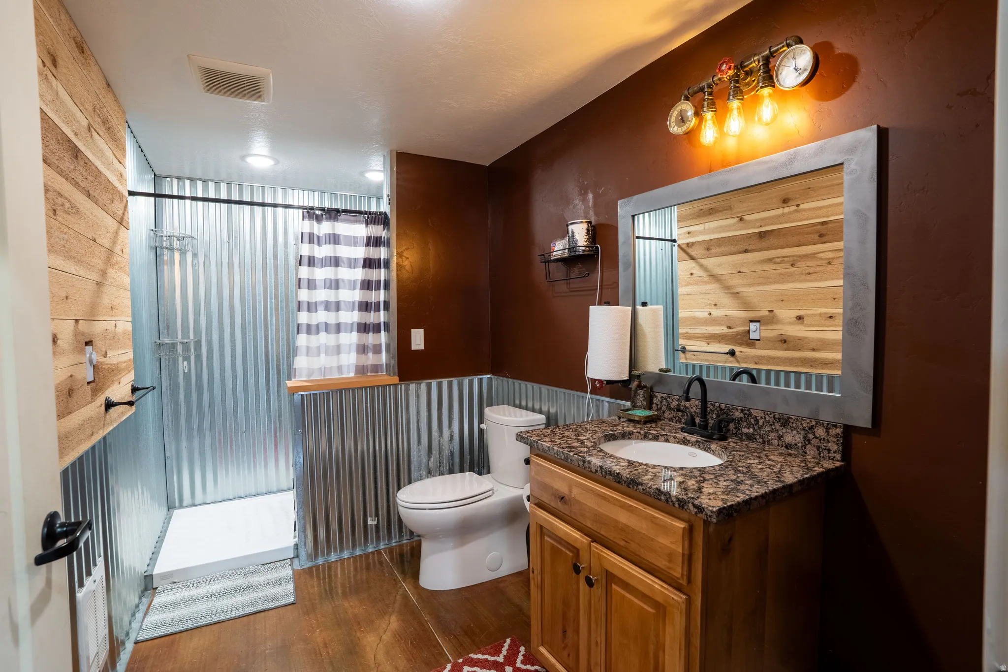 Bathroom featuring vanity, a stall shower, and dark wood-style floors in garage