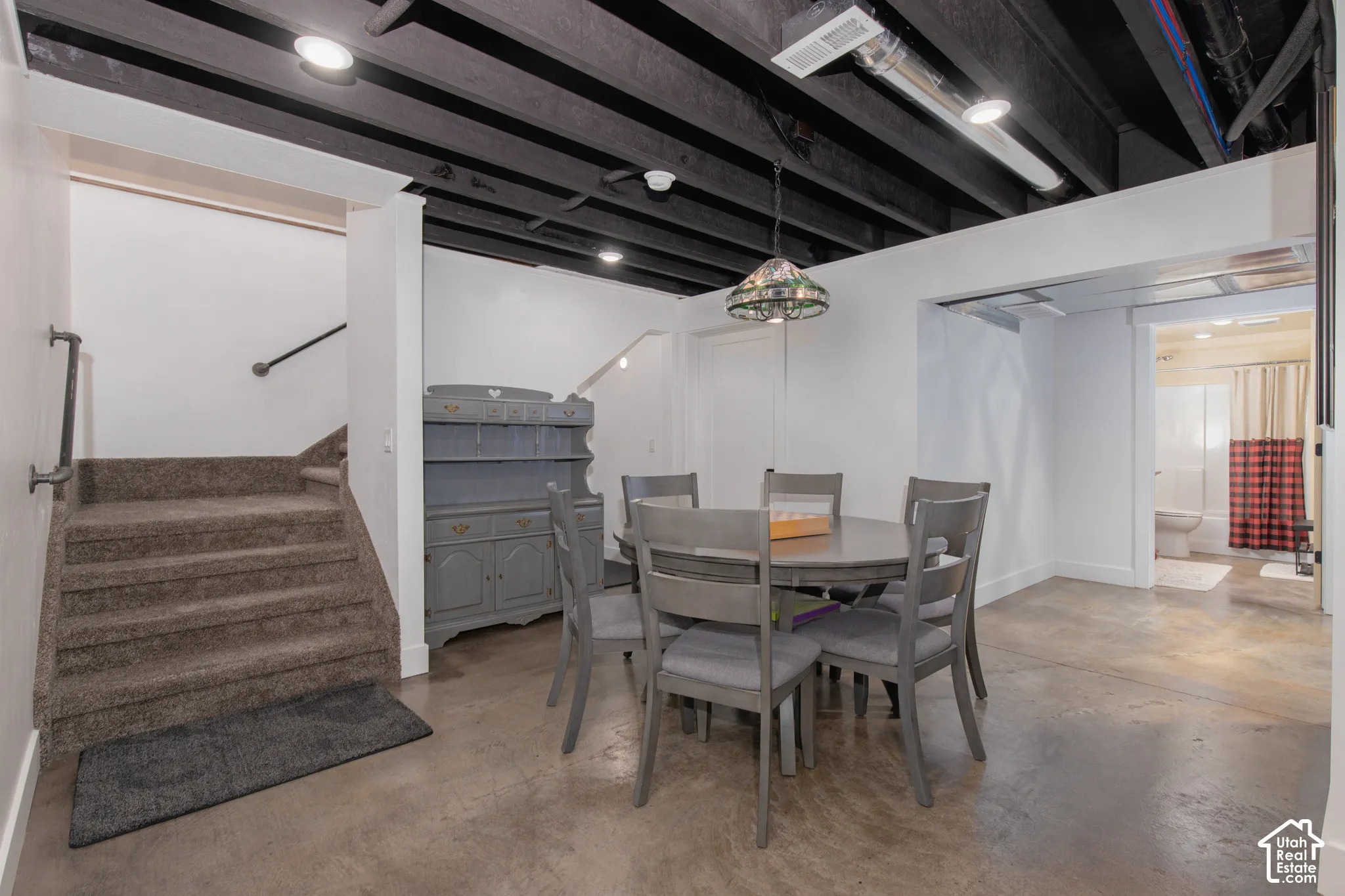 Carpeted staircase with handrail, polished concrete flooring, exposed ceiling beams, recessed lighting, and a bathroom with a shower