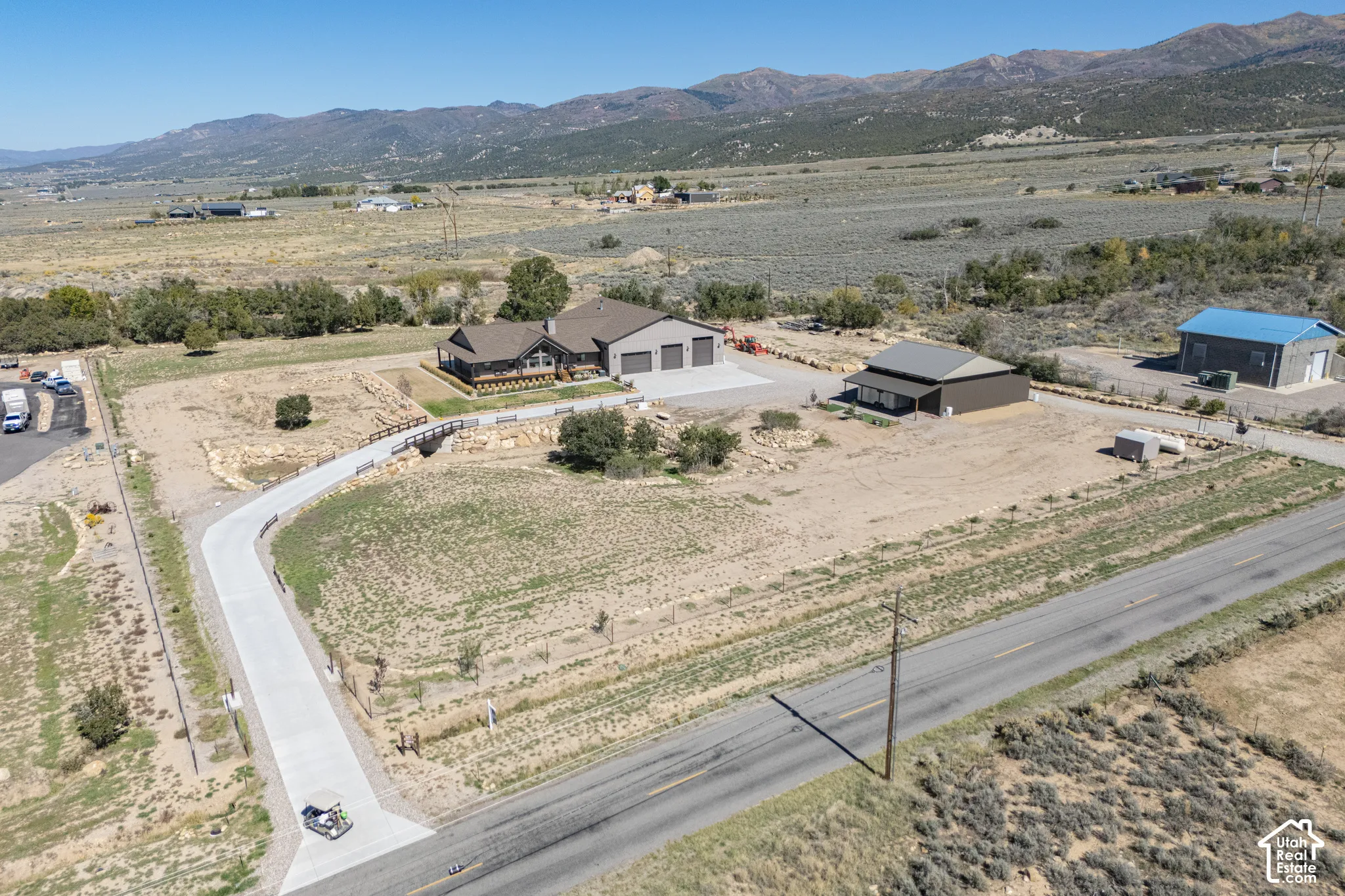 Extensive acreage with a primary residence, a separate auxiliary structure, and a detached garage, all connected by a paved driveway