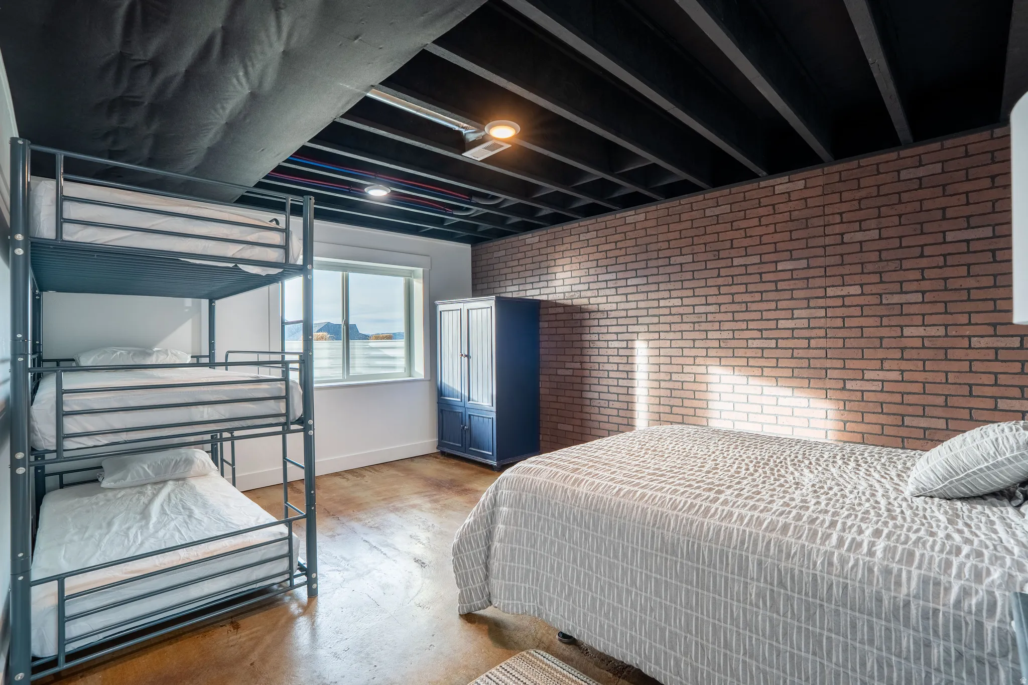 Bedroom 4 featuring brick wall and finished concrete floors