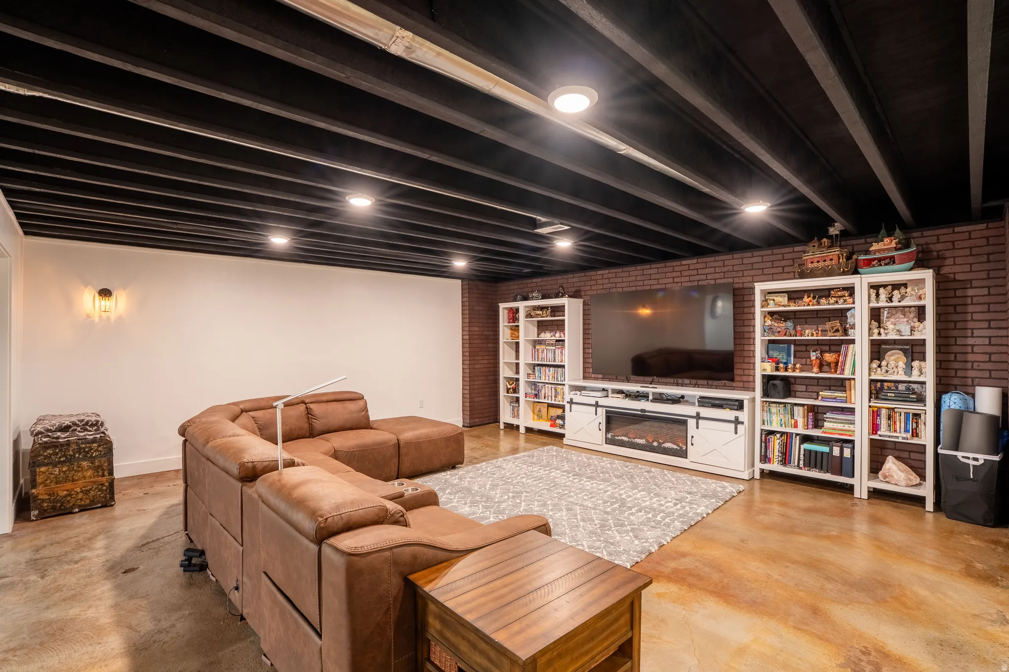 Living room featuring brick wall, finished concrete flooring, theater room
