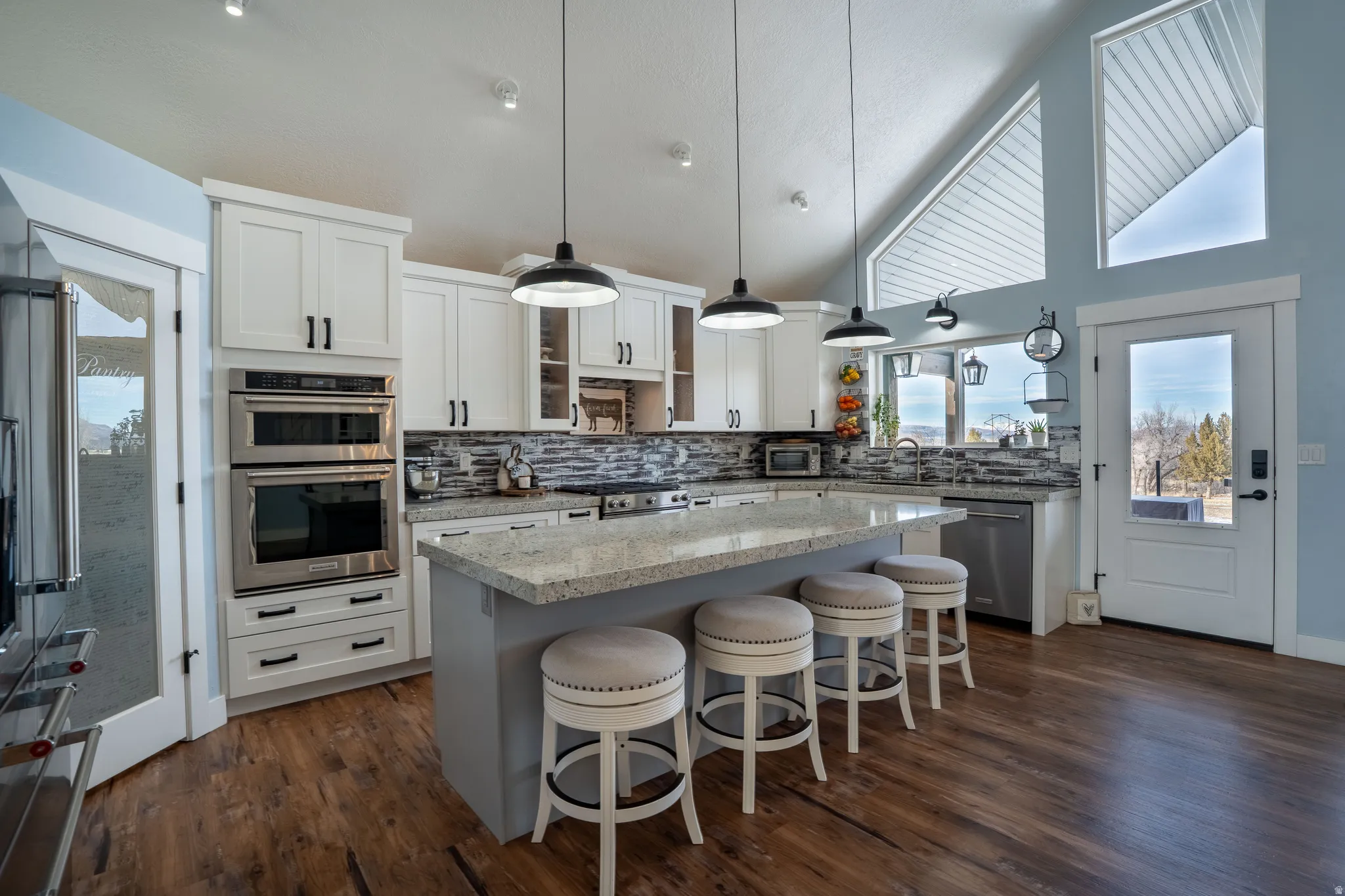 Kitchen featuring a kitchen breakfast bar, pantries, stainless steel appliances, backsplash, and vaulted ceiling