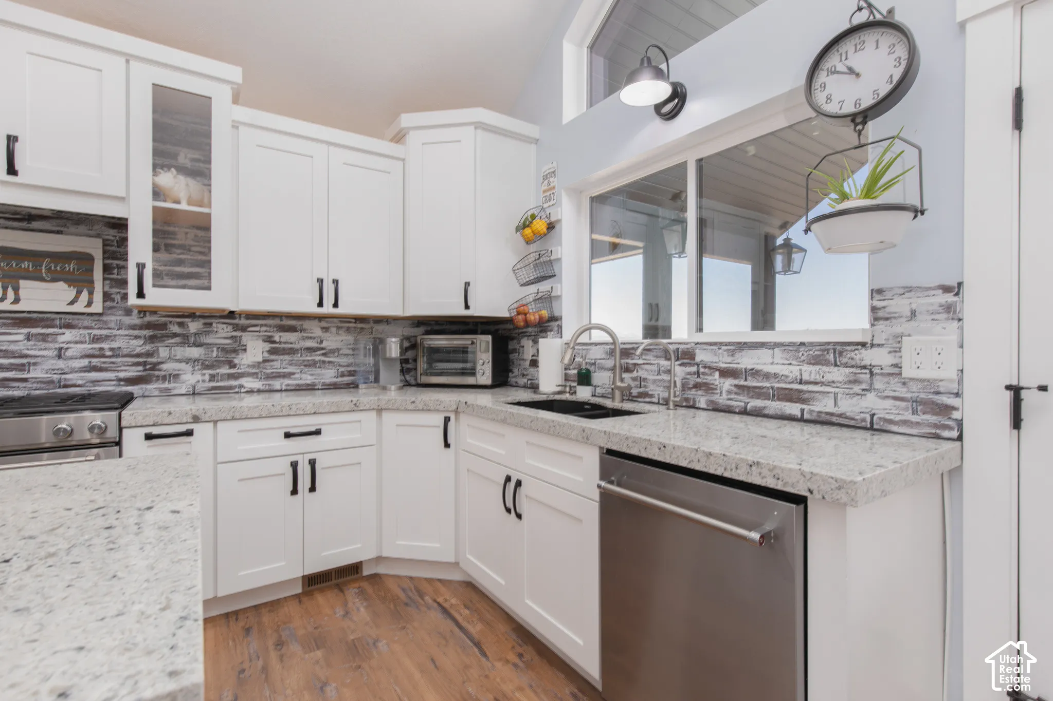 White shaker cabinetry paired with light-toned countertops and a distressed brick-patterned backsplash
