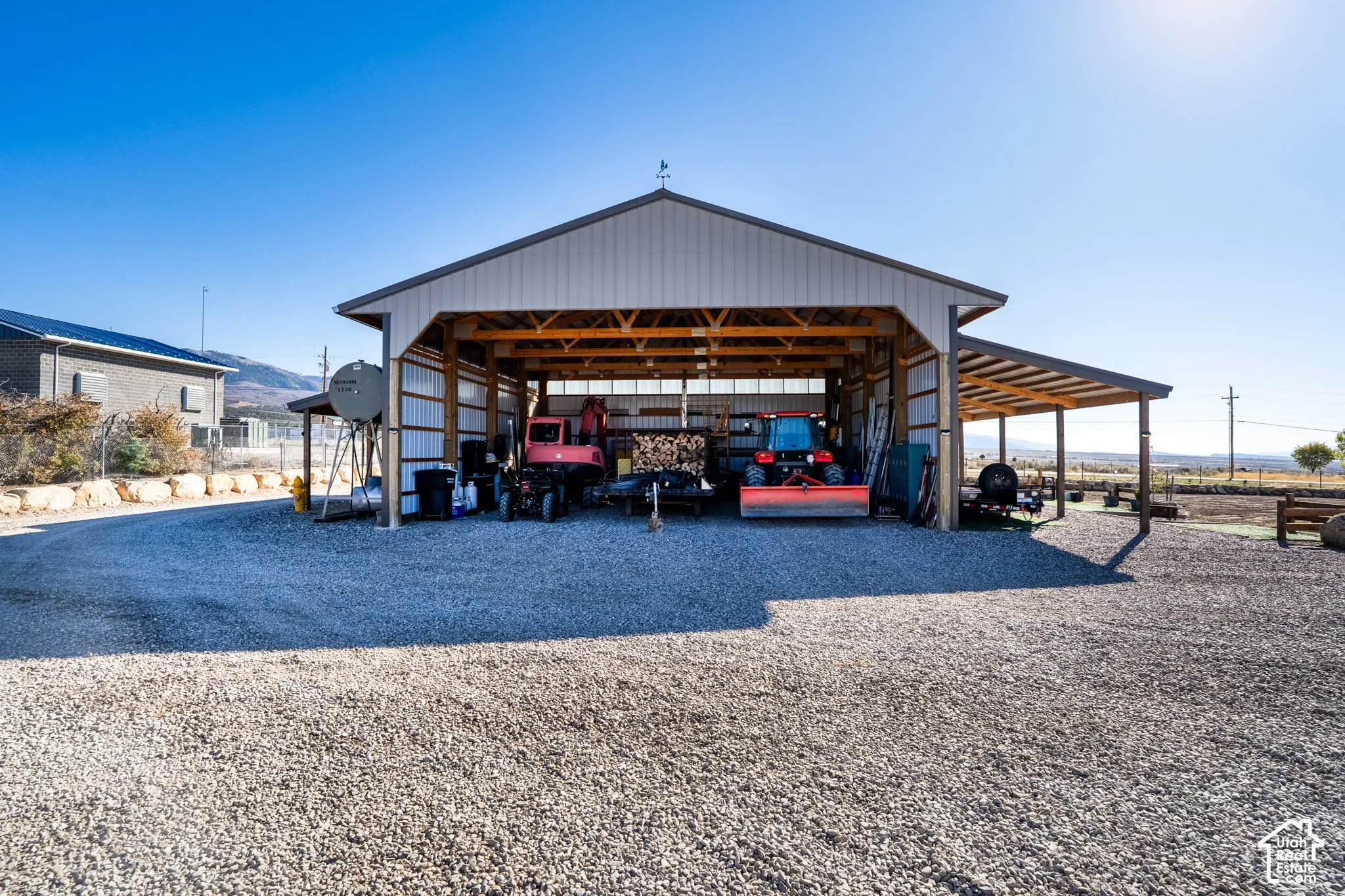 View of pole barn featuring a carport and driveway, overhangs
