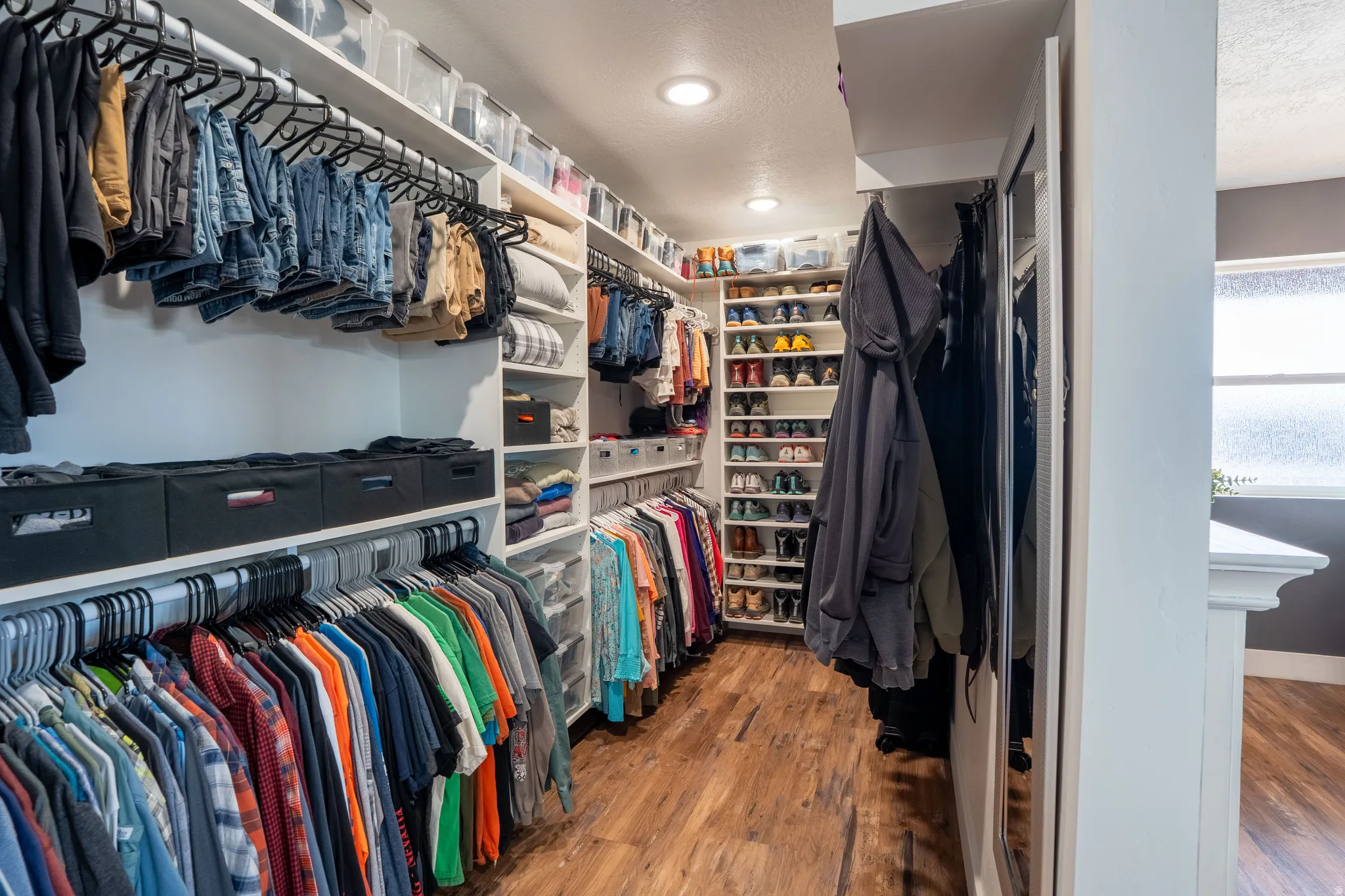 Primary walk-in closet featuring built in cabinets