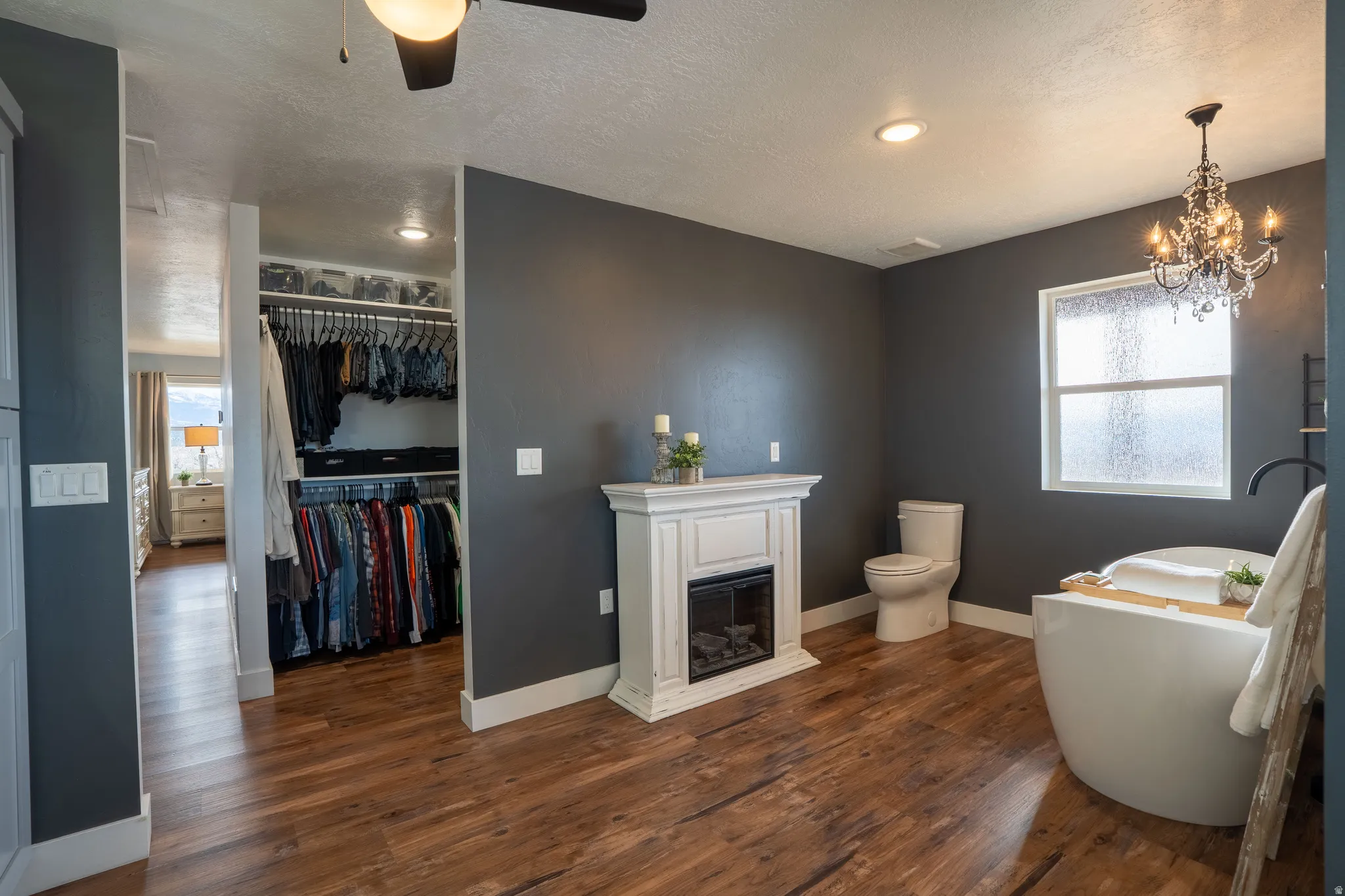 Bathroom with a freestanding bath, electric fireplace, a chandelier, and natural light