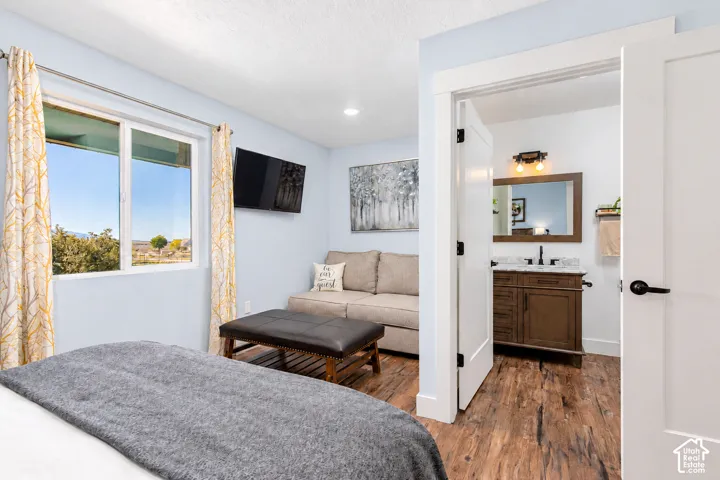 Bright room featuring a window, wall-mounted television, and wood-finish flooring
