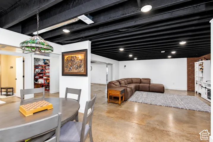 Polished concrete flooring, exposed black ceiling beams, recessed lighting, and a built-in shelving unit