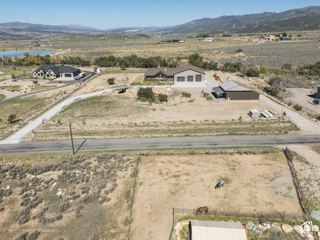 Expansive property featuring a contemporary residence with an attached three-car garage, an additional detached building, and a paved private drive