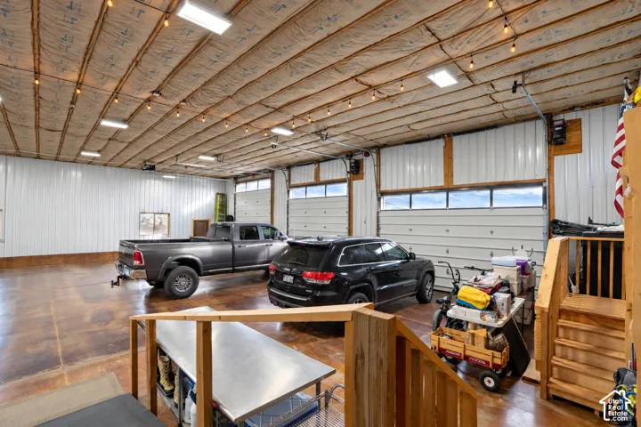 Expansive garage space featuring a concrete floor, multiple overhead doors with integrated windows, and exposed ceiling insulation with ample lighting