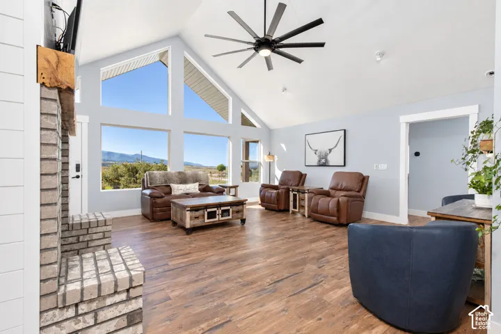 Vaulted ceilings with a ceiling fan, wood-finish flooring, and a brick fireplace