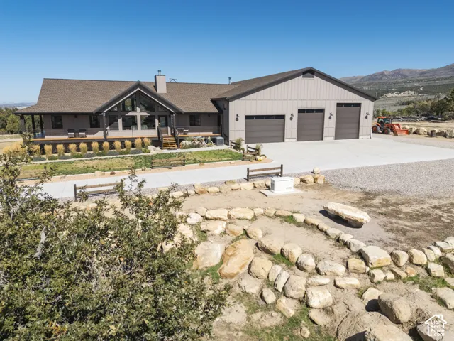 Contemporary home with an expansive concrete driveway, a three-car garage, and a broad front deck