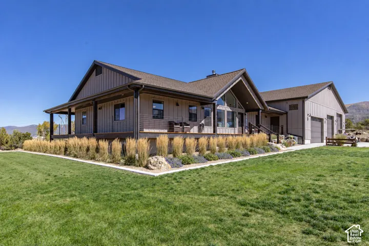 Board and batten exterior with an expansive front lawn, a covered porch, and a two-car garage