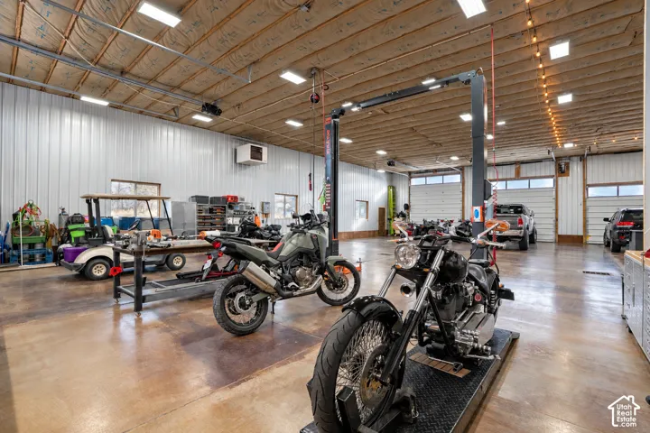 Expansive garage space with high ceilings, multiple roll-up doors, polished concrete flooring, and ample overhead lighting
