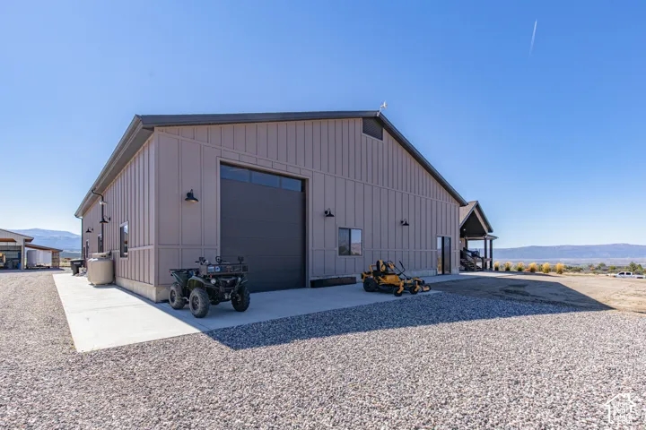 Metal-sided structure with a large overhead door, multiple exterior light fixtures, and a covered entry