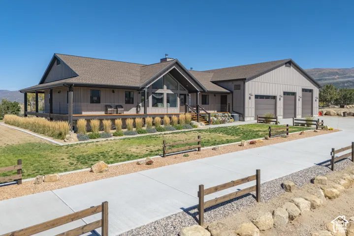 Modern farmhouse exterior featuring board and batten siding, a covered porch, a multi-car garage, large picture windows, and a concrete driveway